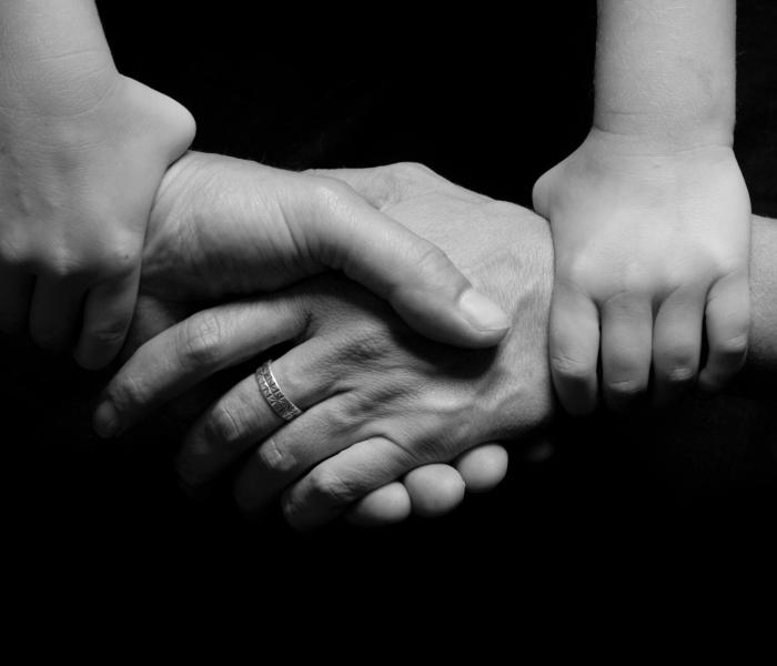 Two hands shaking each other while being held on the wrist by two other hands