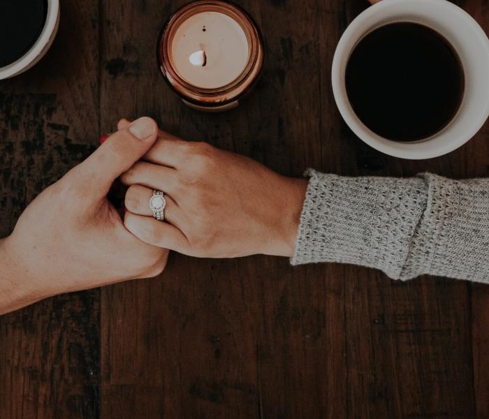Two hands holding each other next to coffee cups