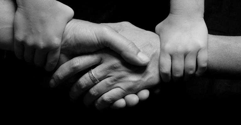 Two hands shaking each other while being held on the wrist by two other hands