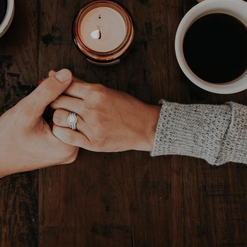 Two hands holding each other next to coffee cups